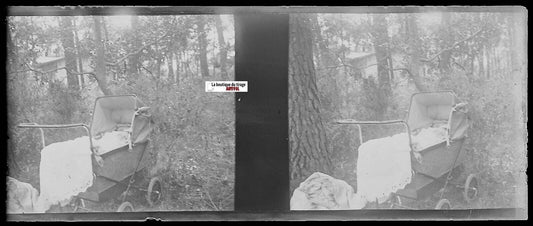 Antique stereoscopic photo of empty baby carriage in forest, early 20th century, black and white negative, 4.5x10.7 cm.