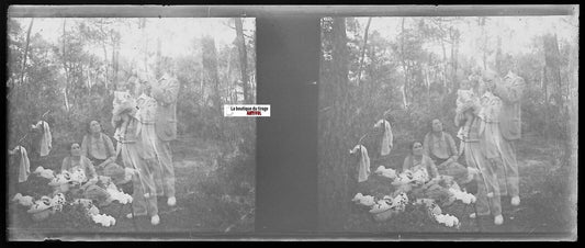 Antique stereoscopic photo negative of a family scene in a forest, early 20th century, man holding a baby, black and white.